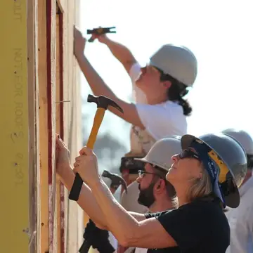 Volunteers hammering nails into wall