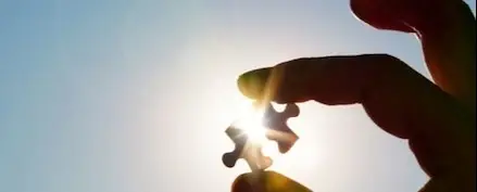 Someone holding a puzzle piece towards the sun.