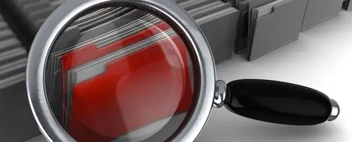 A graphic of a magnifying glass examining folders.