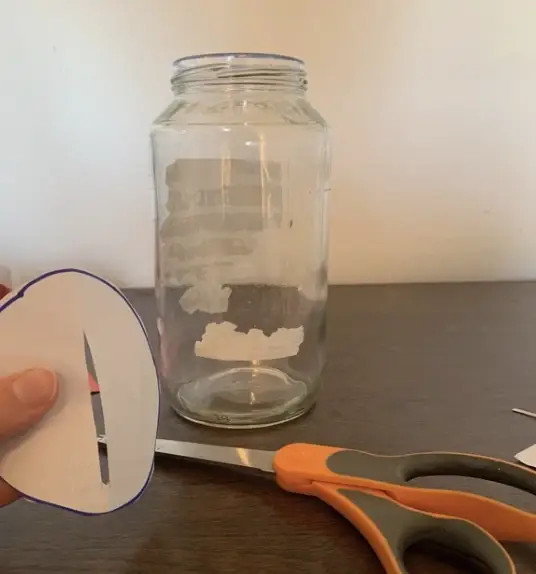 A small circle cut partially in the middle, with a clean jar and scissors in the background.