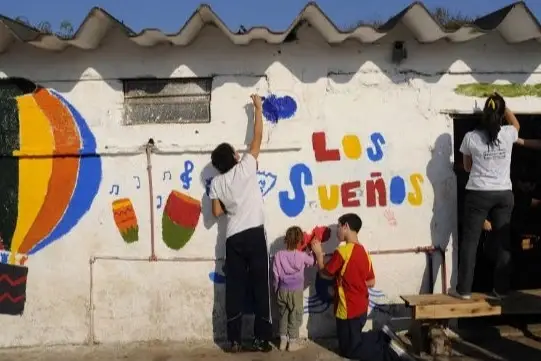 chicos y chicas pintando una fachada