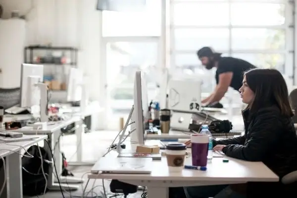 Mujer trabajando frente a computador, muy concentrada