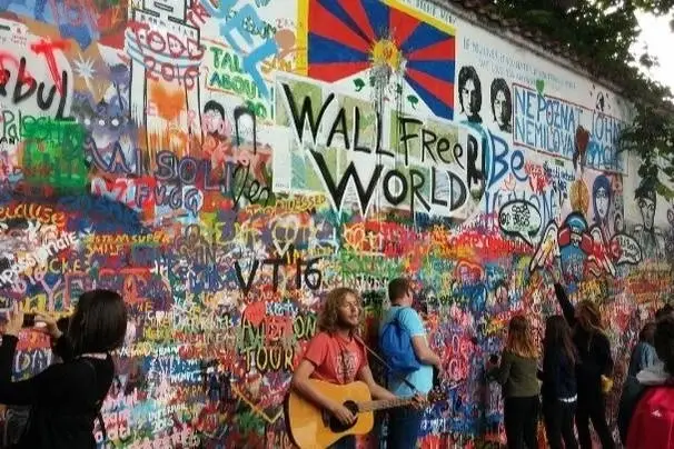 Cantora tocando violão na frente de uma parede cheia de grafites