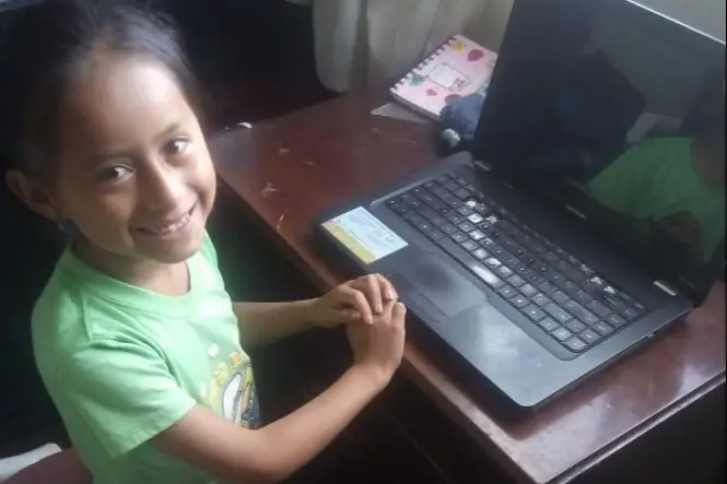 Niña sonriendo frente a su computador