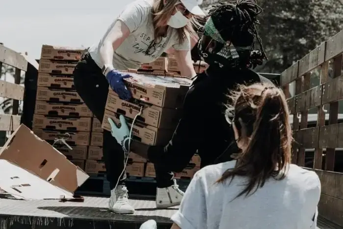 Foto de 3 pessoas ajudando a descarregar materiais de um caminhão.