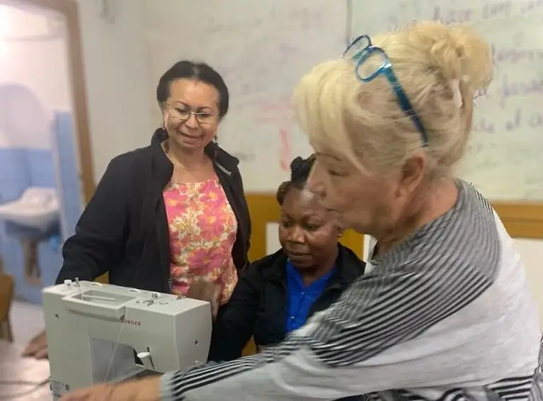 Tres mujeres alrededor de una máquina de coser