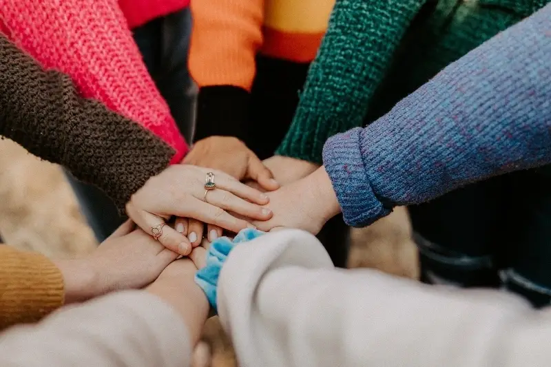 Varias manos de diferentes personas unidas en el centro simbolizando una alianza