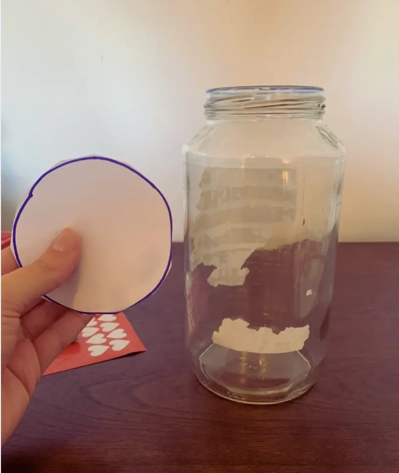 A small circle cut out from a piece of white paper in front of a clean mason jar.