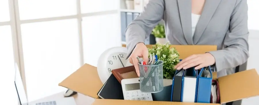 Someone packing up their work desk into a box.