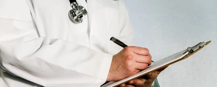 A doctor writing on a clipboard.