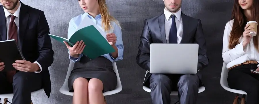 Frou people sitting on chairs doing various work related tasks.