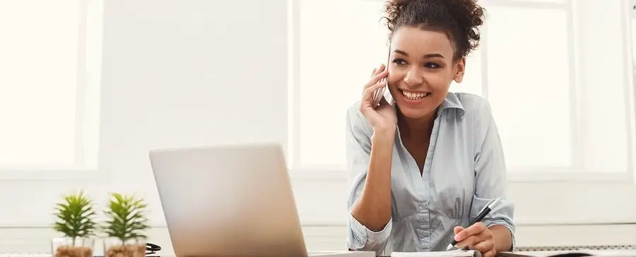 A woman on a desk talking on the phone.