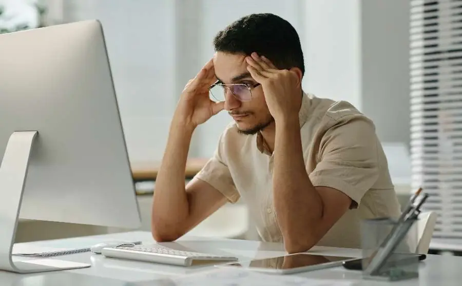 Joven sentado frente a su computadora con expresión preocupada.