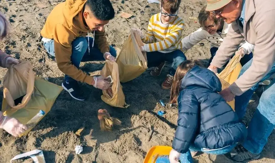 Imagem de crianças recolhendo objetos na areia de uma praia.