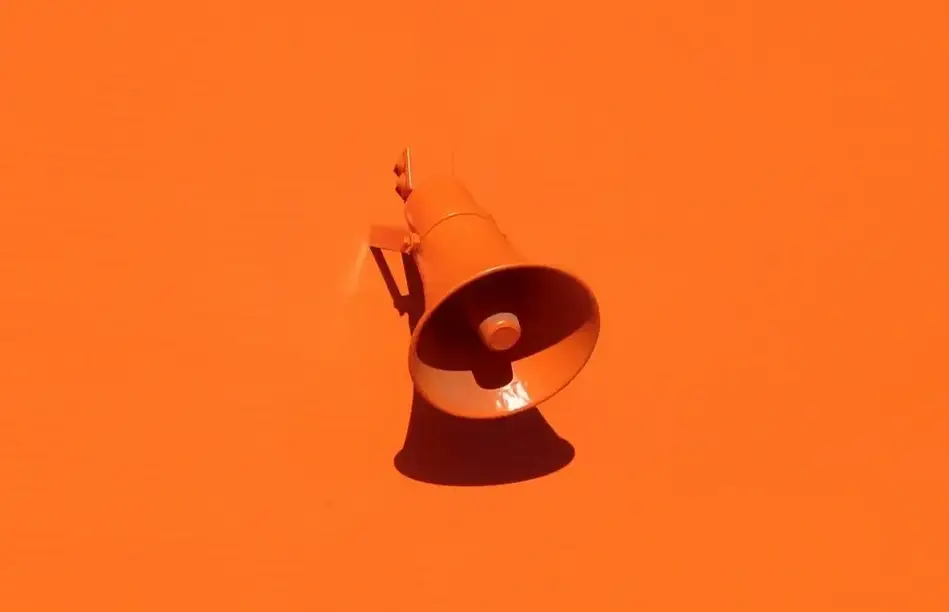 Imagem de um megafone em uma parede laranja