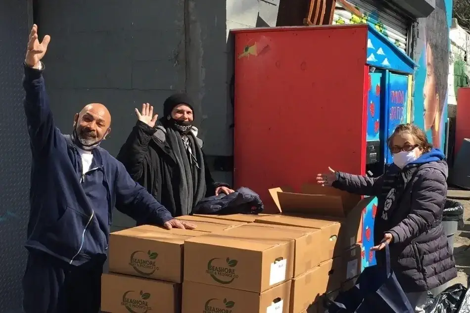 A photograph of the Mott Haven Fridge and several volunteers loading fresh food into the fridge.