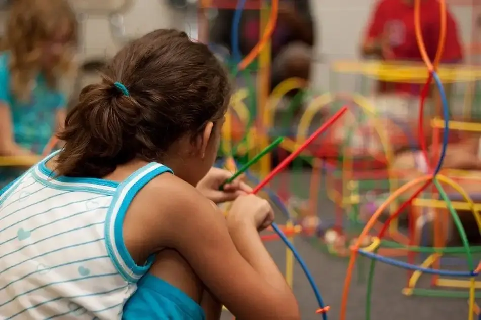 Foto de uma criança brincando com peças de um brinquedo colorido.