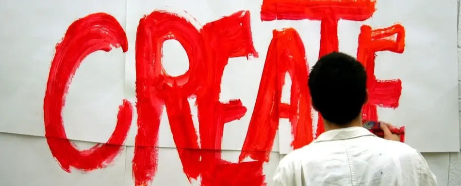 A person painting the word "Create" in red paint.