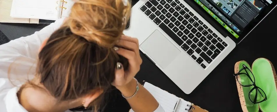 Someone with their head in their hands at her work desk.