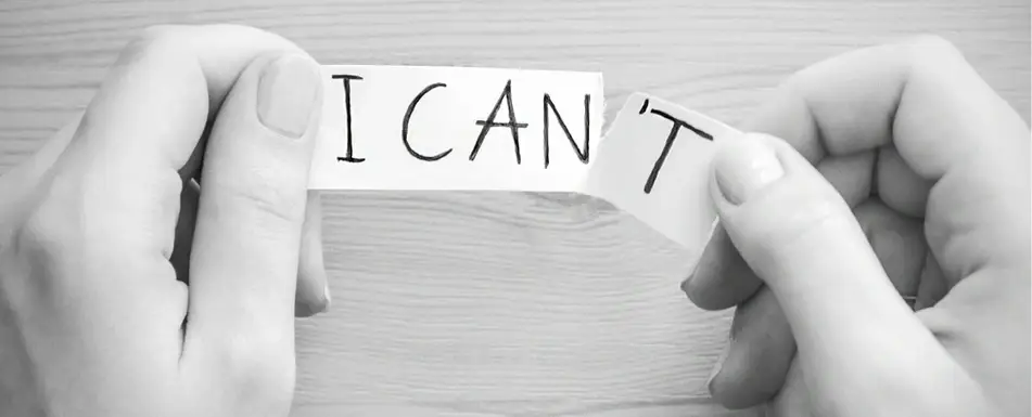 A person tearing up a note that says 'I Can't'.