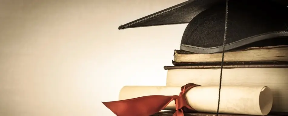 A diploma, a pile of books and a graduation cap.