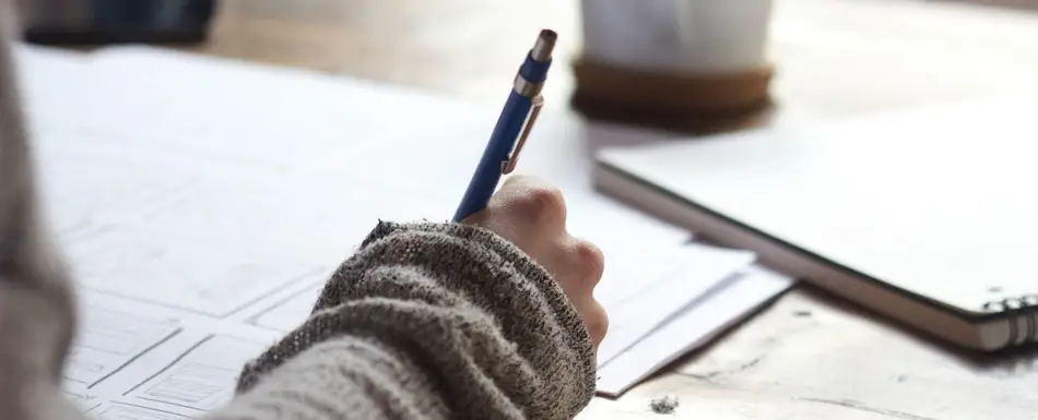 Person writing by hand at a table