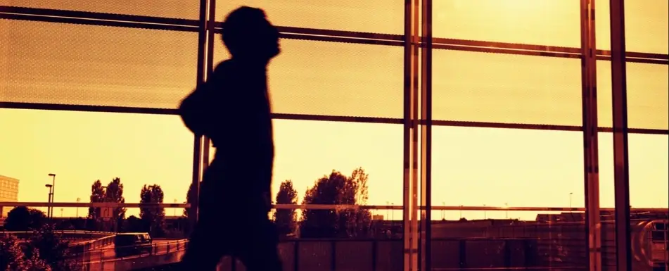 A stressed man walking past a window.