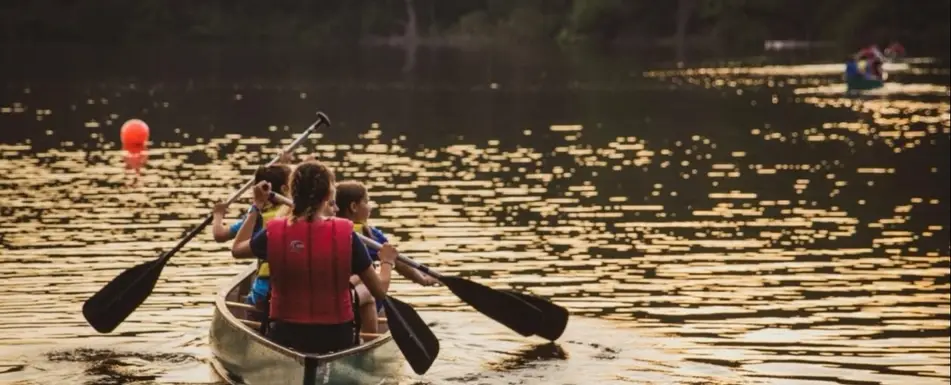 Campers in a canoe sitting on a lake.