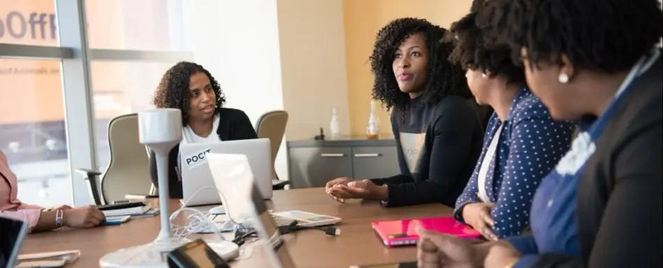 A group of people sitting and talking on a conference table.