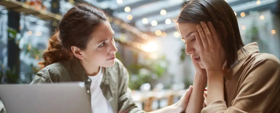 A photograph of a woman comforting a friend who is combatting workplace stress and burnout.