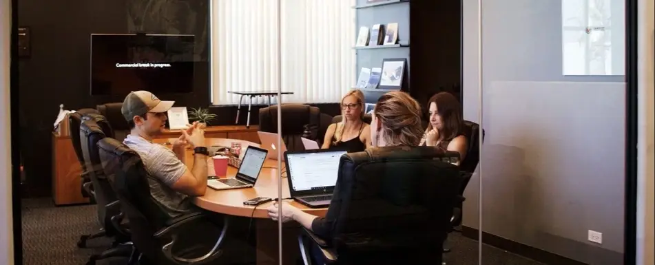 A group of people sitting and talking in a conference room.