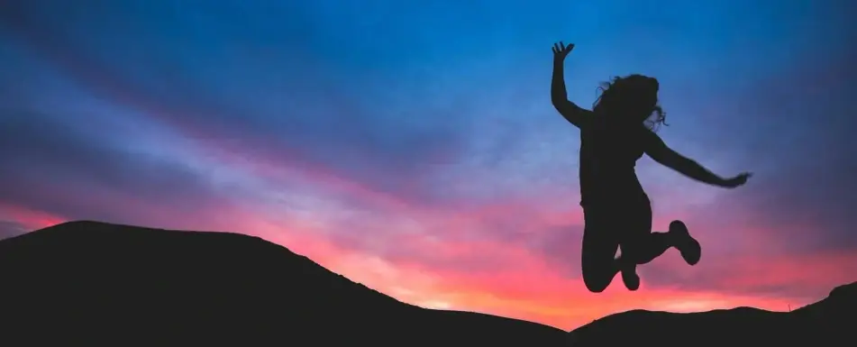 Mujer saltando con atardecer en el fondo