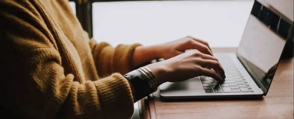 A woman's hands working at a laptop.