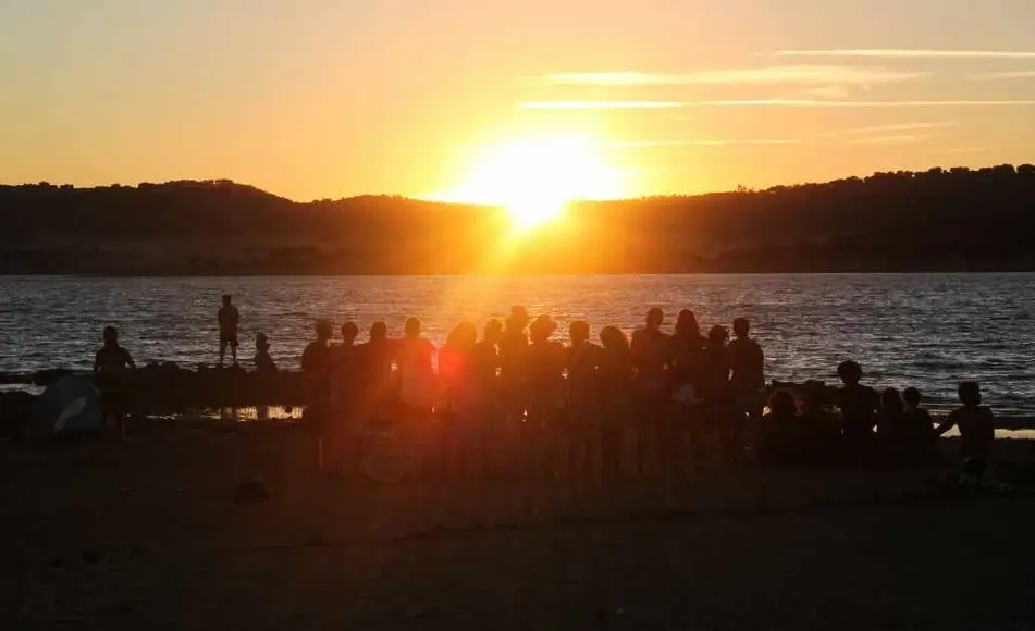 Grupo grande de personas observa un atardecer en la naturaleza