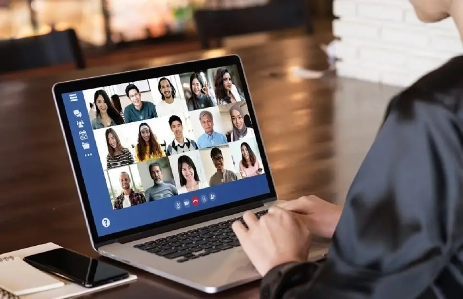 A imagem mostra diversas pessoas em uma videoconferência virtual, cada uma em sua janela de vídeo, refletindo diversidade e conectividade.