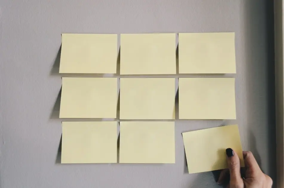 Mano pegando post-it amarillo en una pared