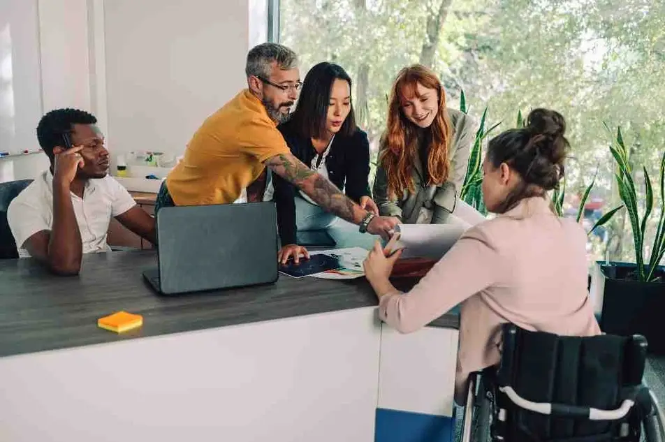 Equipo de personas reunidas alrededor de una mesa de trabajo.