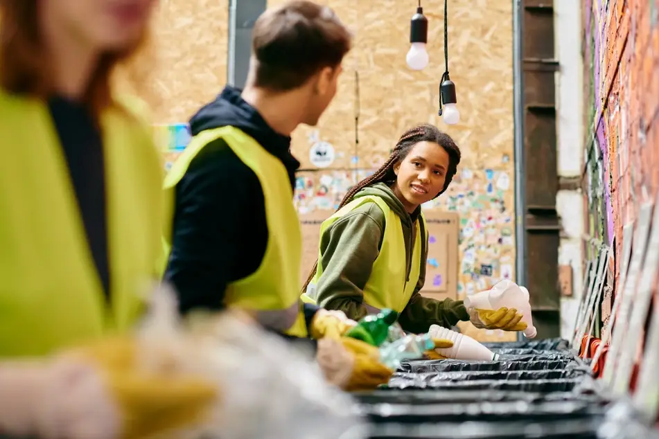 A group of multiracial volunteers collect trash at a park as part of a social-impact opportunity.