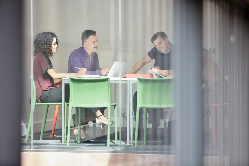 Group of multi-racial colleagues sit at desk and discuss duties as board members.