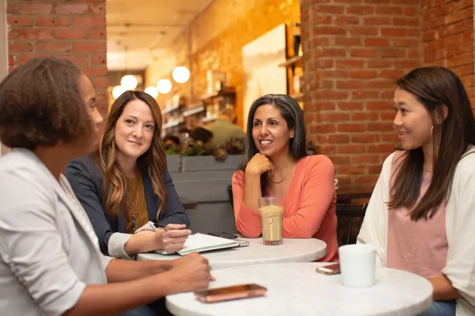 4 mujeres sentadas conversando en un café