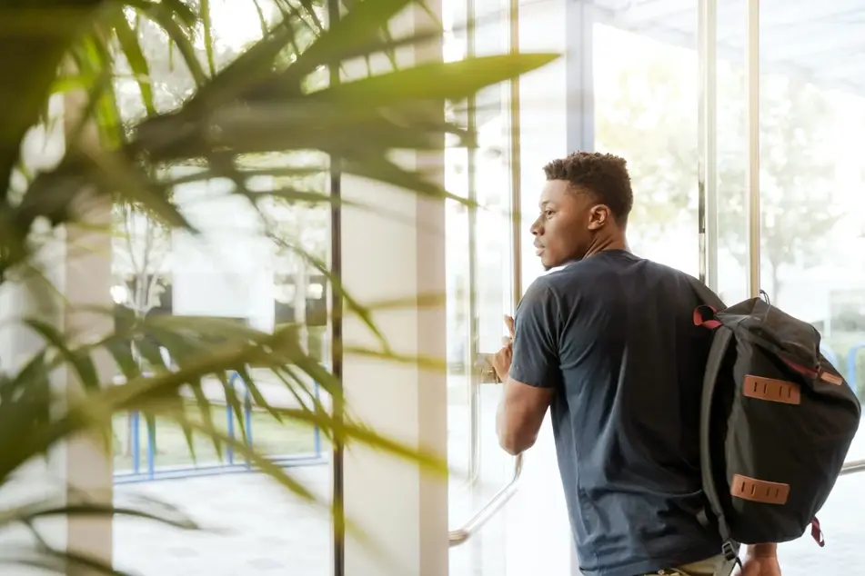 A man with a backpack leaves work for the day.