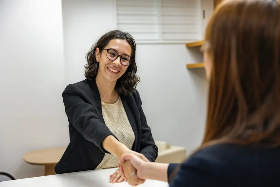 Mujer estrechando la mano de otra después de una entrevista de trabajo