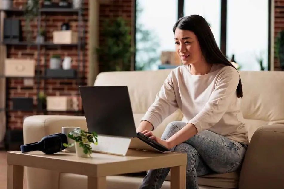 Mujer sonriendo mientras mira la pantalla de su computadora.