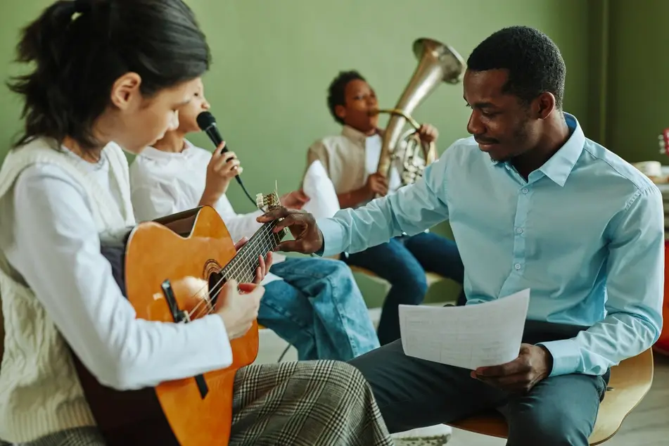 Organizer at music and arts organization teaches students how to play instruments