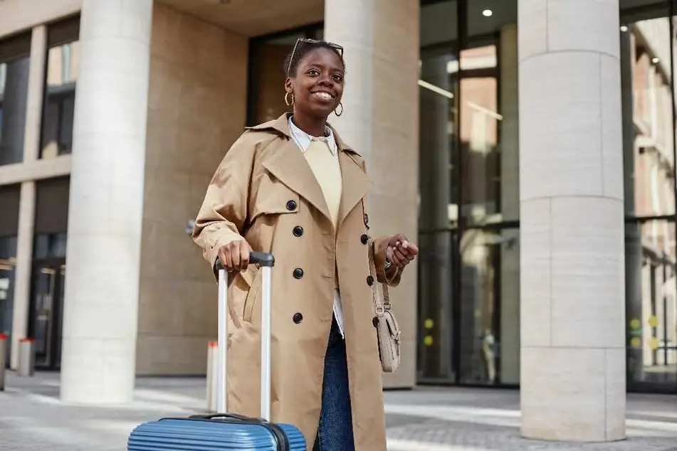 Mujer joven sosteniendo una maleta para viajar.