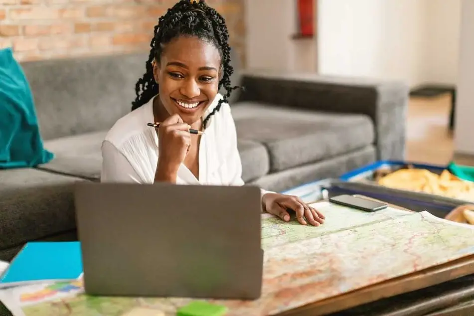 Mujer sentada en un escritorio trabajando con su computadora y un mapa.