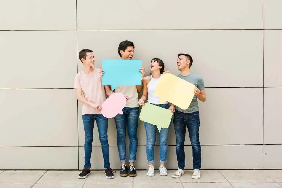 Grupo de jóvenes sosteniendo burbujas de diálogo de papel