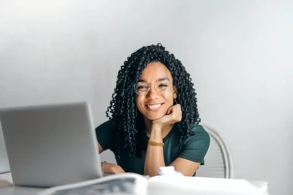 Mujer joven sonriendo frente a una computadora