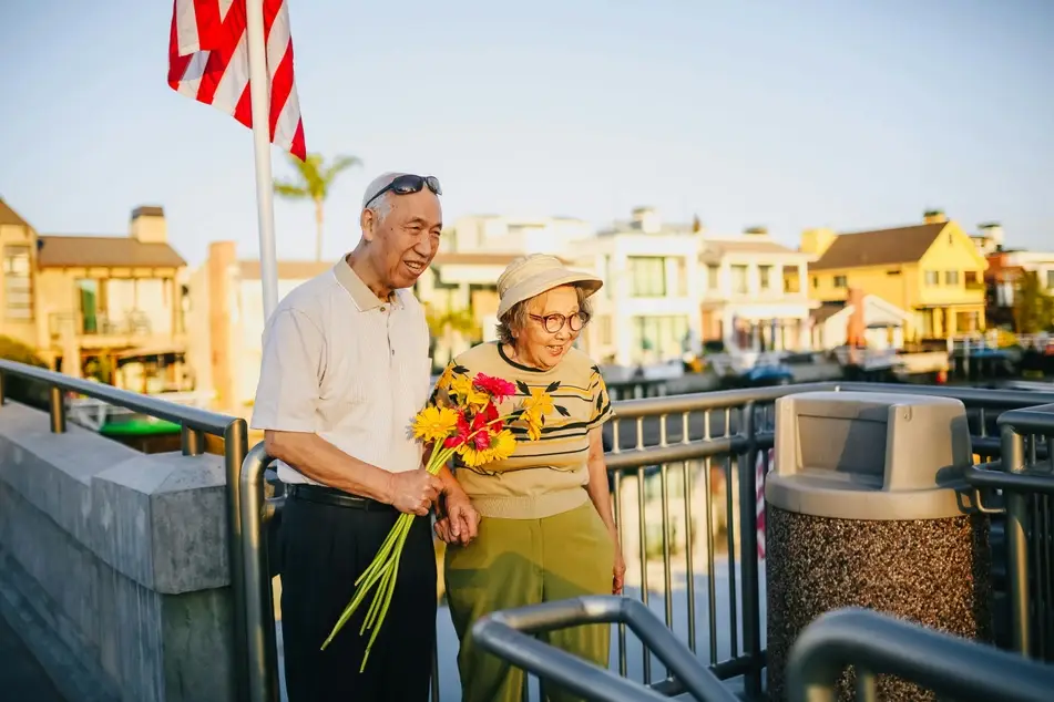 two people walking, smiling, and holding flowers