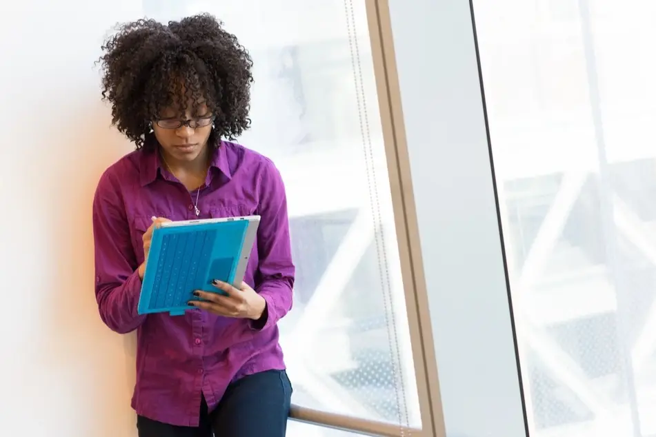 Black woman using tablet in front of office window